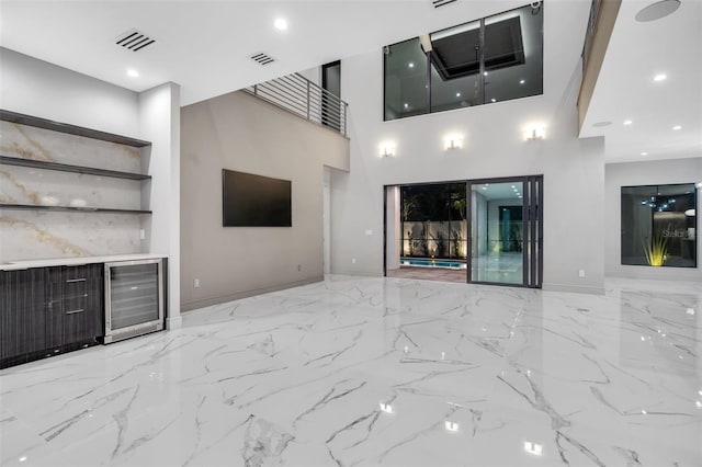 unfurnished living room with marble finish floor, a towering ceiling, visible vents, and recessed lighting