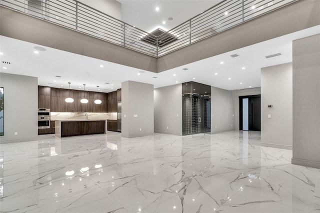 unfurnished living room with baseboards, marble finish floor, a towering ceiling, and recessed lighting