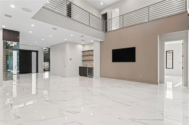 unfurnished living room featuring visible vents, baseboards, marble finish floor, recessed lighting, and a high ceiling