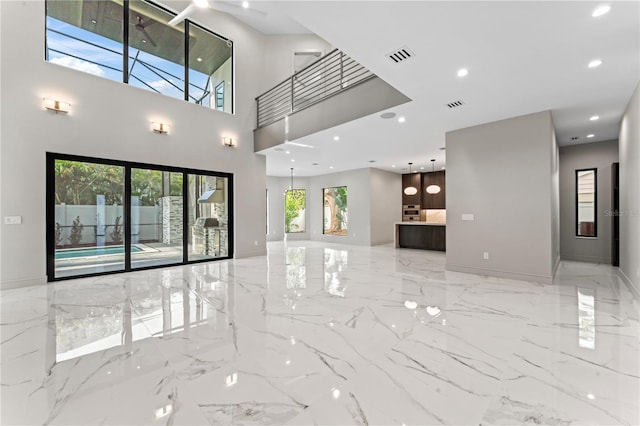unfurnished living room featuring marble finish floor, a towering ceiling, visible vents, and recessed lighting