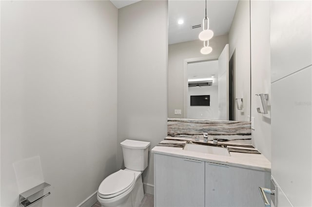 bathroom with baseboards, toilet, and vanity