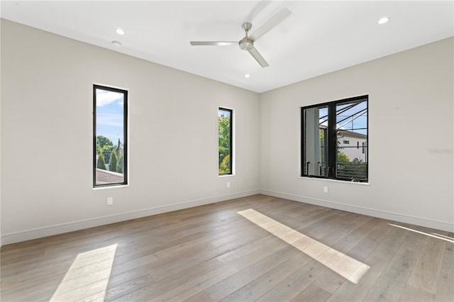 empty room featuring plenty of natural light, baseboards, light wood-style floors, and ceiling fan