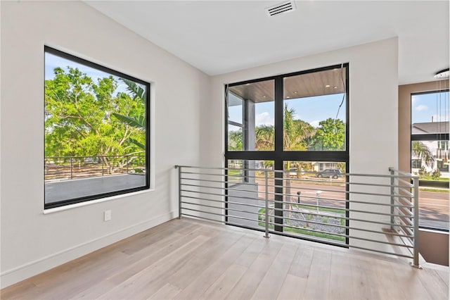 unfurnished room featuring wood finished floors, baseboards, and visible vents