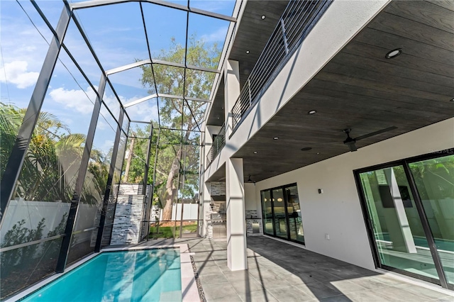 view of pool with glass enclosure, fence, and a patio area