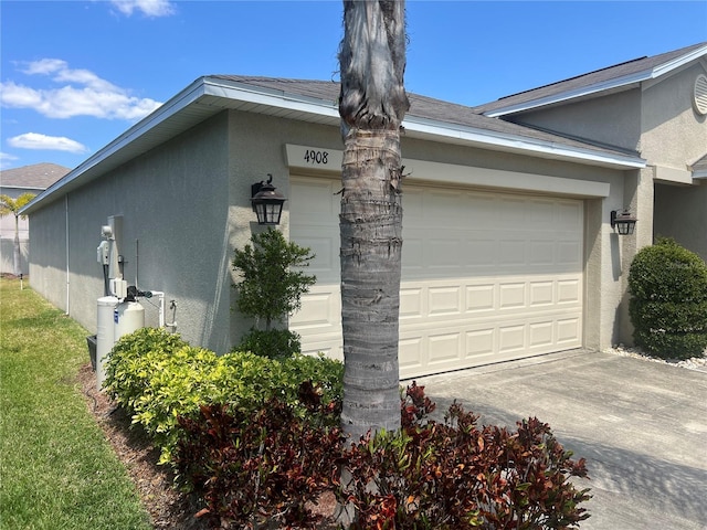 view of side of home with stucco siding, a garage, and concrete driveway