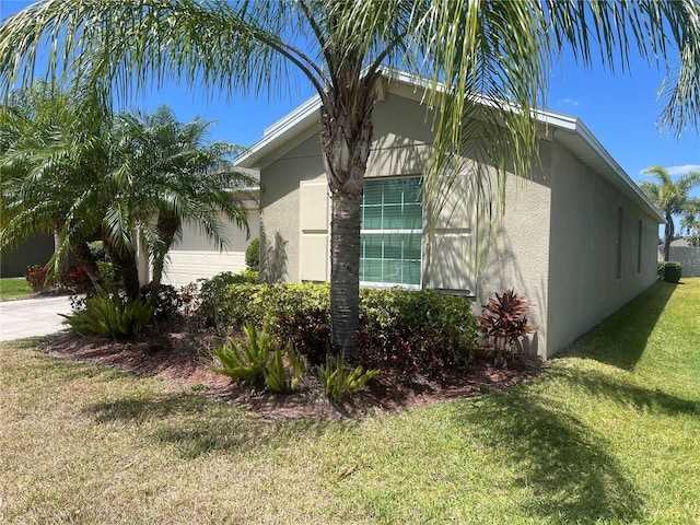 view of side of home with stucco siding, a garage, and a lawn