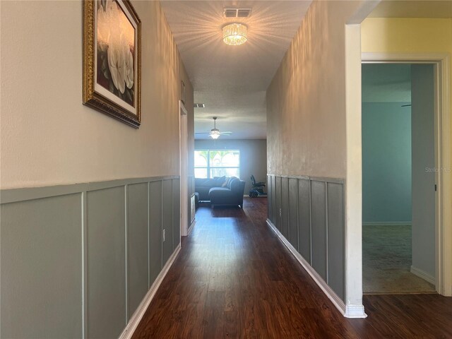corridor with dark wood finished floors and wainscoting