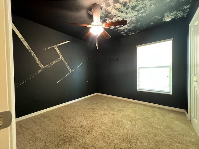 spare room with carpet floors, ceiling fan, and baseboards