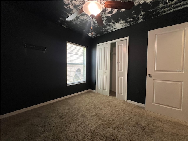 unfurnished bedroom with carpet, a closet, ceiling fan, and baseboards