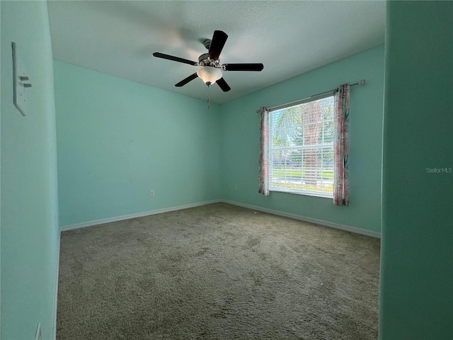carpeted empty room featuring ceiling fan and baseboards