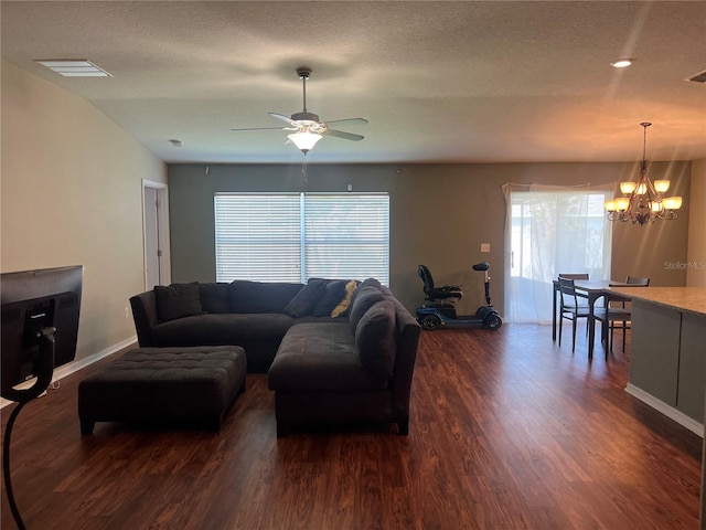 living area with dark wood-type flooring, a chandelier, healthy amount of natural light, baseboards, and a textured ceiling