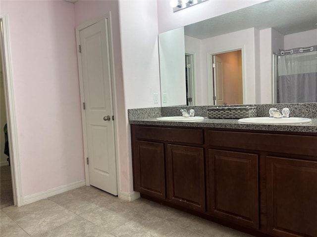 full bath with double vanity, baseboards, and tile patterned flooring