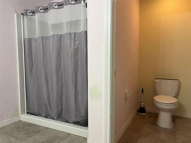 bathroom with a shower stall, toilet, baseboards, and tile patterned flooring