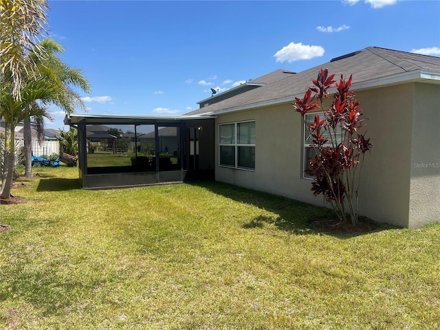 back of house with a sunroom, a yard, and stucco siding