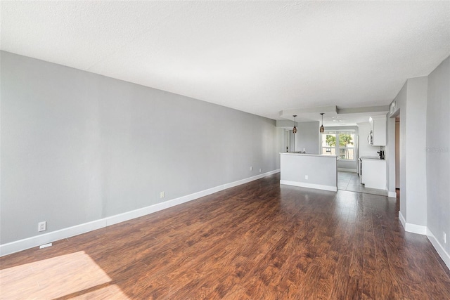 unfurnished living room featuring dark wood-style floors and baseboards