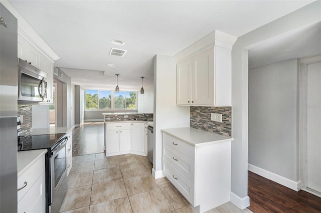 kitchen featuring white cabinetry, light countertops, appliances with stainless steel finishes, and visible vents