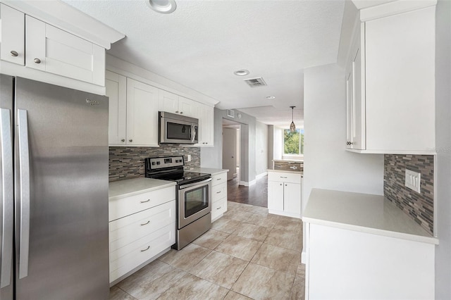 kitchen featuring light countertops, decorative backsplash, visible vents, white cabinets, and appliances with stainless steel finishes