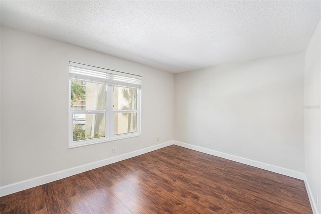 empty room with dark wood finished floors, baseboards, and a textured ceiling