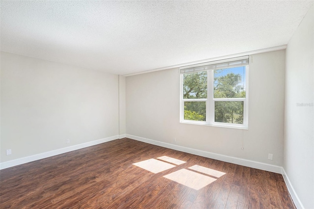 empty room featuring baseboards, hardwood / wood-style flooring, and a textured ceiling