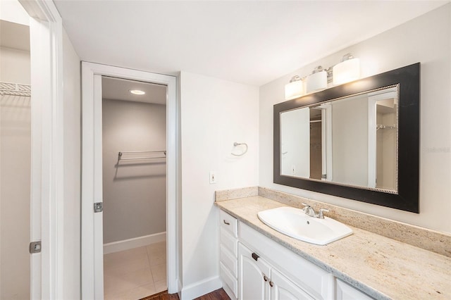 full bath featuring baseboards, a spacious closet, and vanity