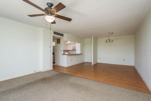 30 Turner St Unit 502, Clearwater, FL 33756 - unfurnished living room featuring carpet flooring, ceiling fan with notable chandelier, a textured ceiling, visible vents, and wood finished floors
