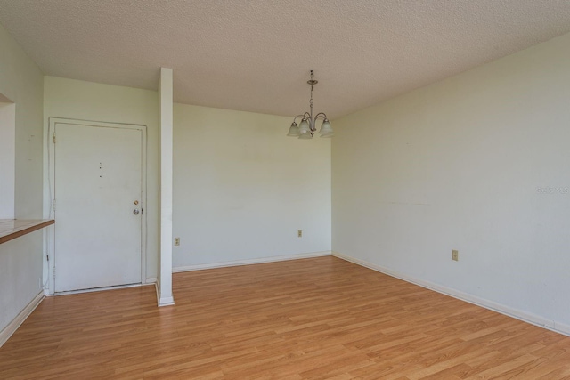 30 Turner St Unit 502, Clearwater, FL 33756 - spare room with a notable chandelier, baseboards, light wood-style floors, and a textured ceiling