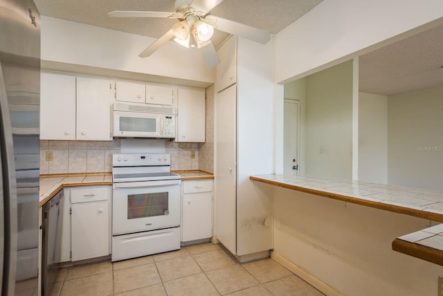 30 Turner St Unit 502, Clearwater, FL 33756 - kitchen with backsplash, tile counters, appliances with stainless steel finishes, a textured ceiling, and white cabinets