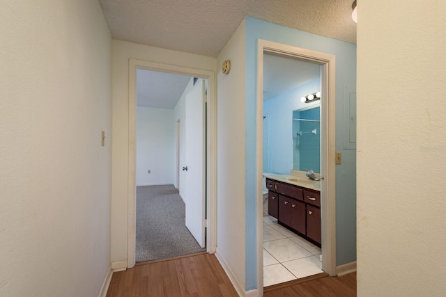 30 Turner St Unit 502, Clearwater, FL 33756 - hallway with a sink, baseboards, light wood-style floors, and a textured ceiling