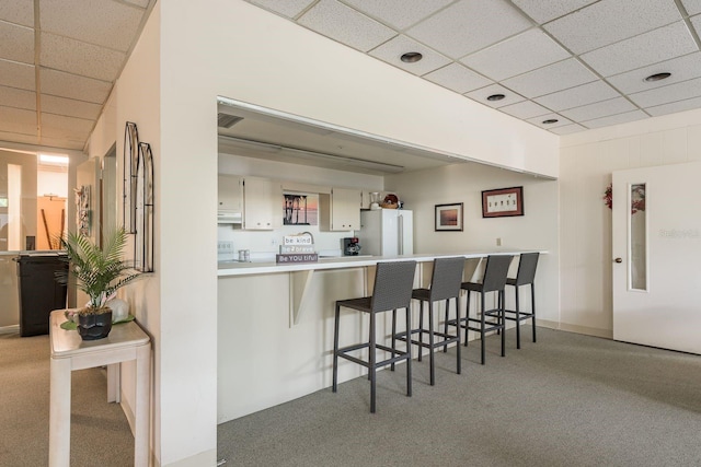 30 Turner St Unit 502, Clearwater, FL 33756 - kitchen featuring light countertops, a kitchen bar, carpet floors, a paneled ceiling, and freestanding refrigerator