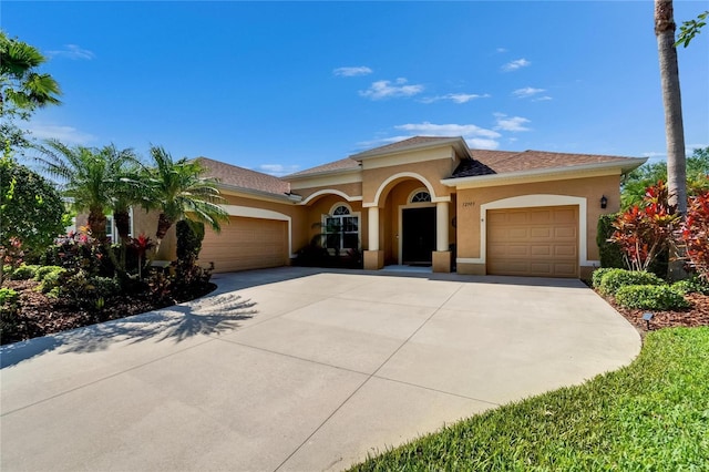 mediterranean / spanish-style home with driveway, stucco siding, and an attached garage