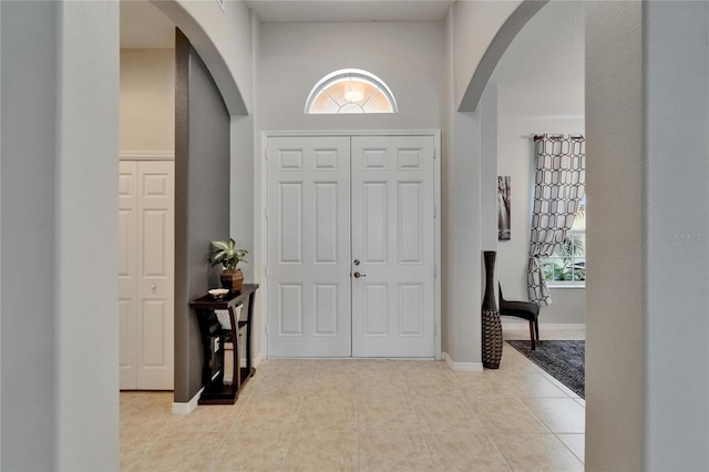 entryway featuring baseboards, arched walkways, and tile patterned flooring