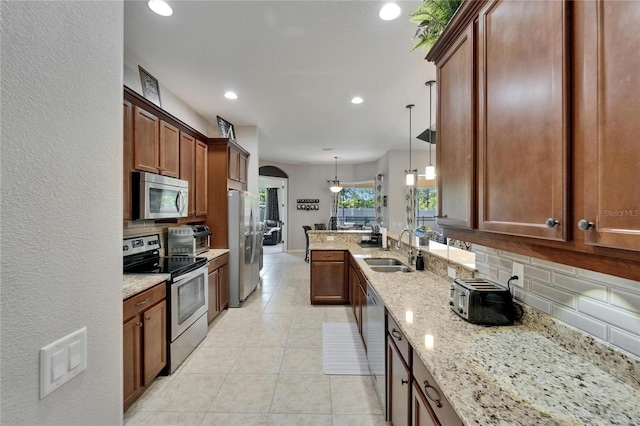kitchen with tasteful backsplash, a sink, appliances with stainless steel finishes, recessed lighting, and light stone countertops