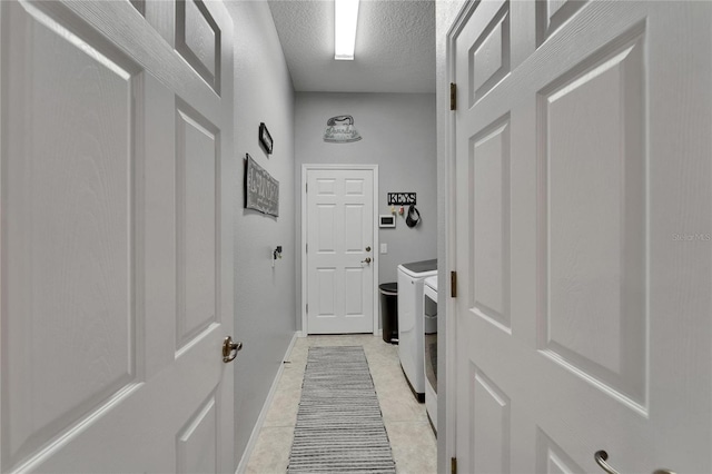 laundry room featuring baseboards, washer and dryer, laundry area, a textured ceiling, and light tile patterned flooring