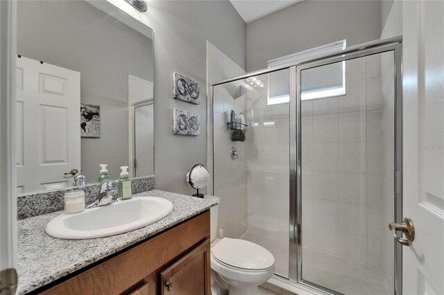 full bath featuring toilet, vanity, and a stall shower
