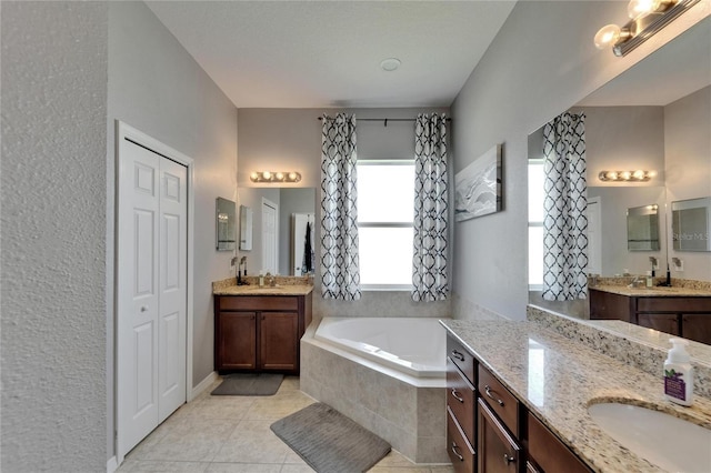 bathroom featuring a sink, a bath, two vanities, and tile patterned flooring