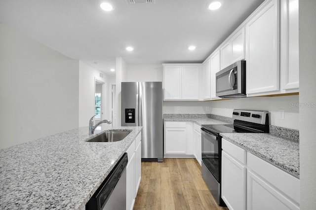 kitchen with light wood-style flooring, a sink, white cabinets, and appliances with stainless steel finishes