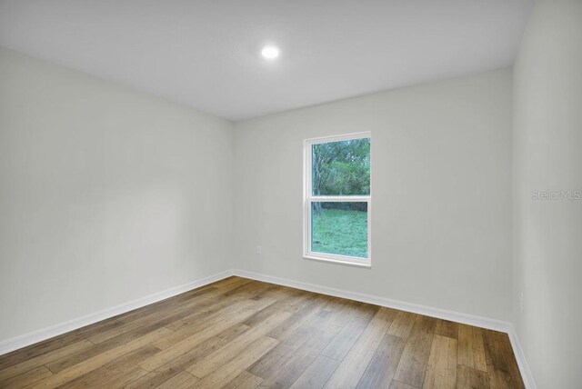 empty room with baseboards and wood-type flooring