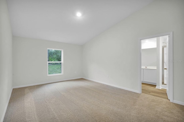 unfurnished room featuring baseboards, lofted ceiling, and carpet