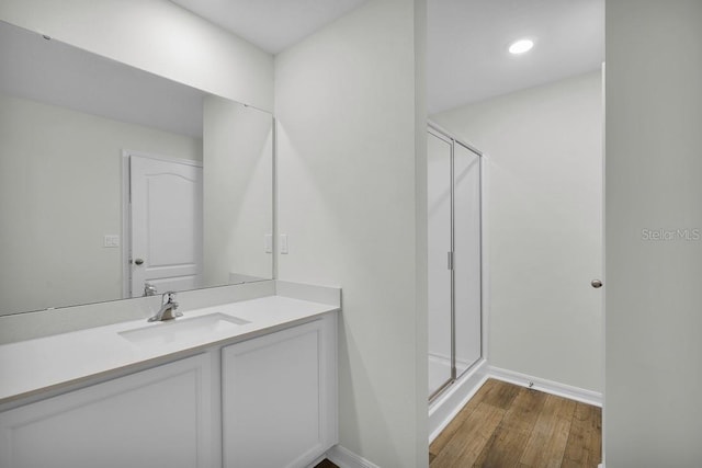 full bathroom with a shower stall, baseboards, wood finished floors, and vanity