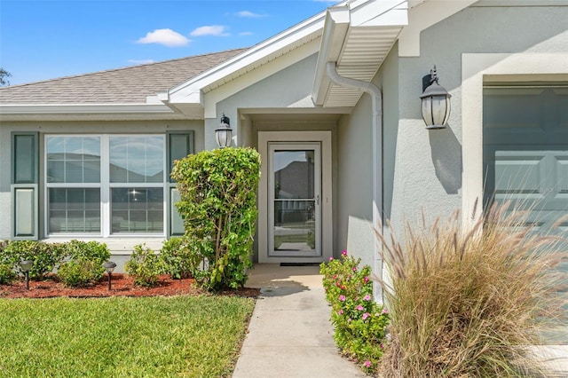 16302 Vine Cliff Ave, Hudson, FL 34667 - view of exterior entry with stucco siding and a shingled roof