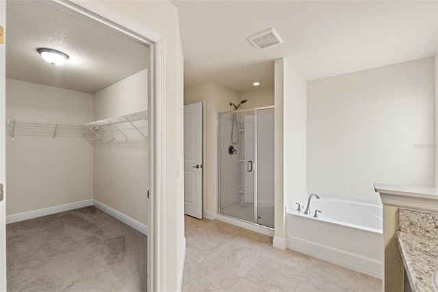 16302 Vine Cliff Ave, Hudson, FL 34667 - full bathroom with a spacious closet, a textured ceiling, a shower stall, tile patterned floors, and a garden tub