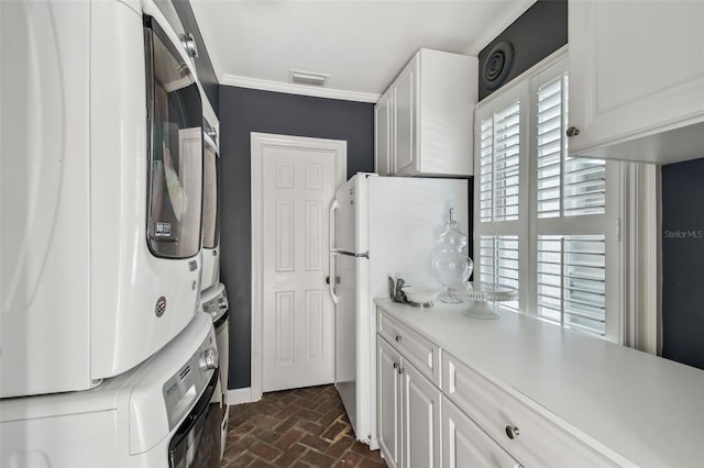 3313 W Mullen Ave, Tampa, FL 33609 - washroom featuring crown molding, brick floor, stacked washer / dryer, visible vents, and cabinet space