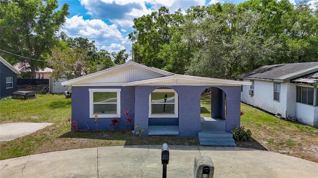 bungalow with brick siding, a porch, and a front yard