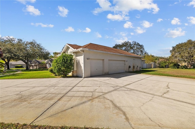 13750 Dowling Ln, Odessa, FL 33556 - view of side of home featuring stucco siding, driveway, an attached garage, and a lawn
