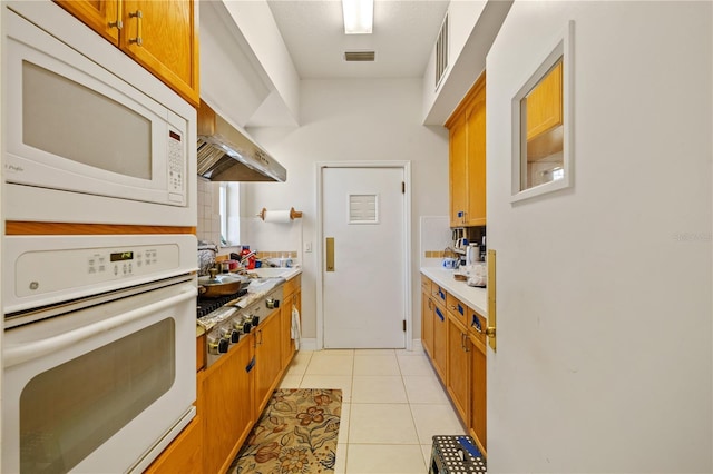 13750 Dowling Ln, Odessa, FL 33556 - kitchen featuring white appliances, light countertops, light tile patterned flooring, and brown cabinetry
