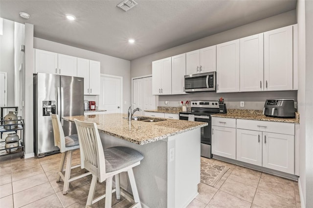 7334 Ashcroft Dr, Wesley Chapel, FL 33545 - kitchen featuring a sink, light stone countertops, stainless steel appliances, a kitchen island with sink, and visible vents