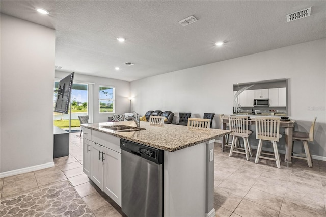 7334 Ashcroft Dr, Wesley Chapel, FL 33545 - kitchen with stainless steel appliances, a sink, light stone counters, an island with sink, and visible vents