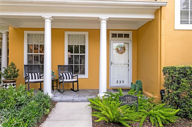 view of exterior entry with covered porch and stucco siding