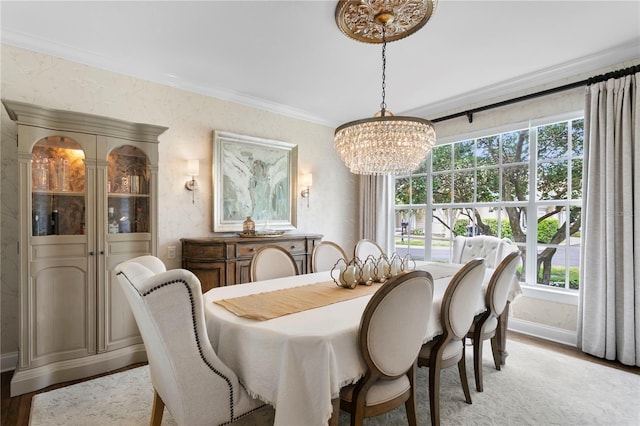 dining space with light wood finished floors, baseboards, an inviting chandelier, and ornamental molding