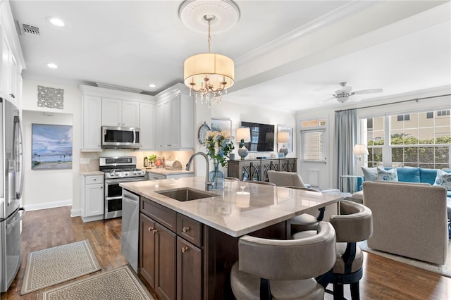 kitchen featuring crown molding, dark wood-type flooring, visible vents, stainless steel appliances, and a sink